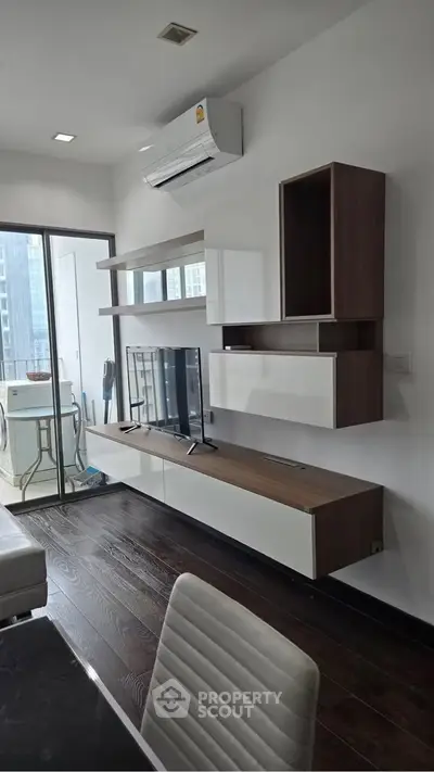 Modern living room with sleek furniture and balcony view in a high-rise apartment.