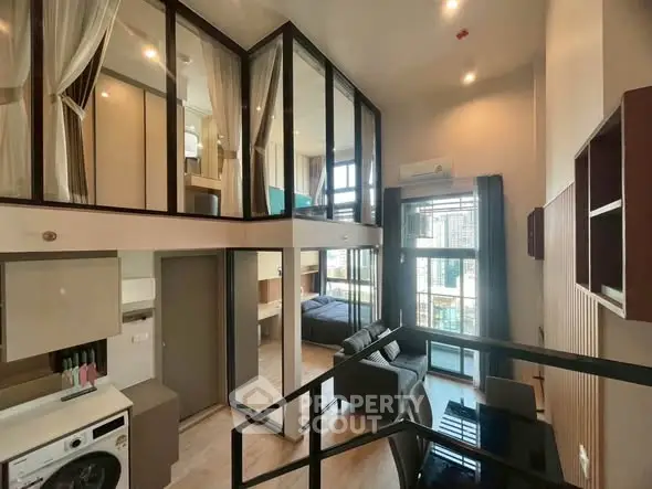 Modern loft apartment with high ceilings and large windows, featuring a cozy living area and mezzanine bedroom.