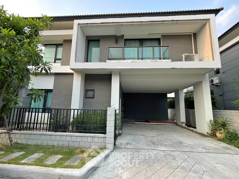 Modern two-story house with balcony and driveway in a serene neighborhood.