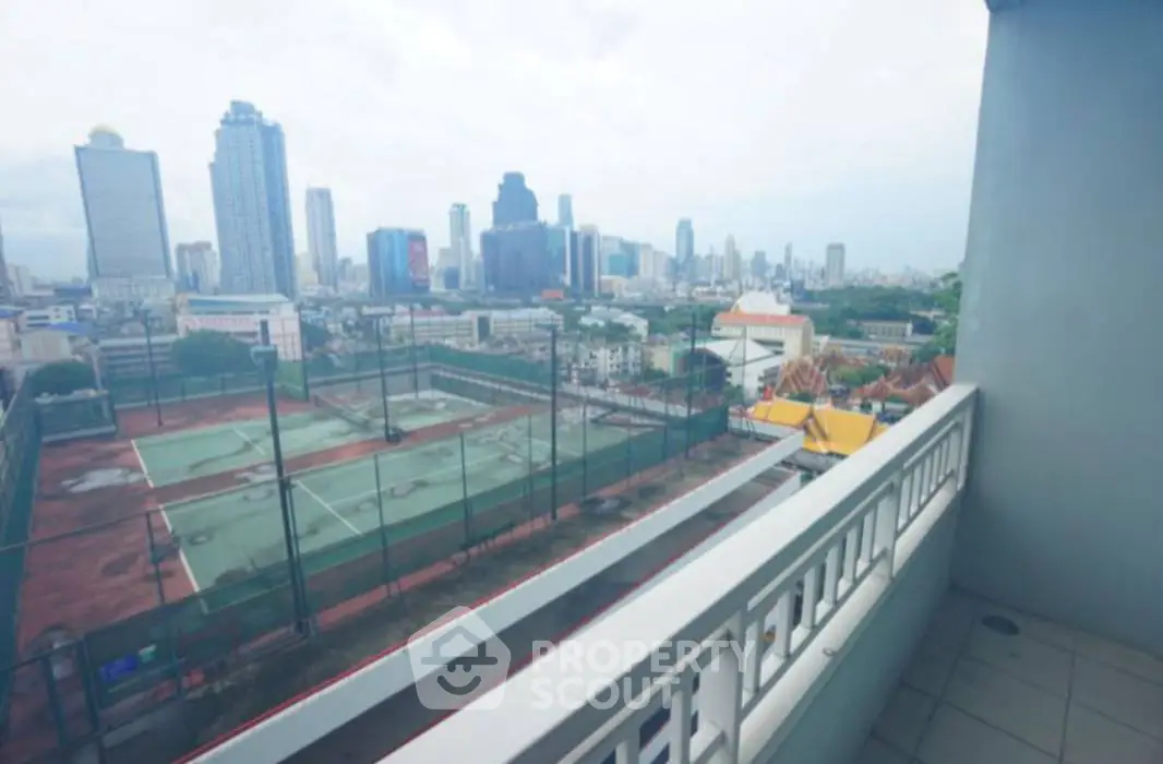Stunning cityscape view from a spacious balcony overlooking tennis courts and skyline.