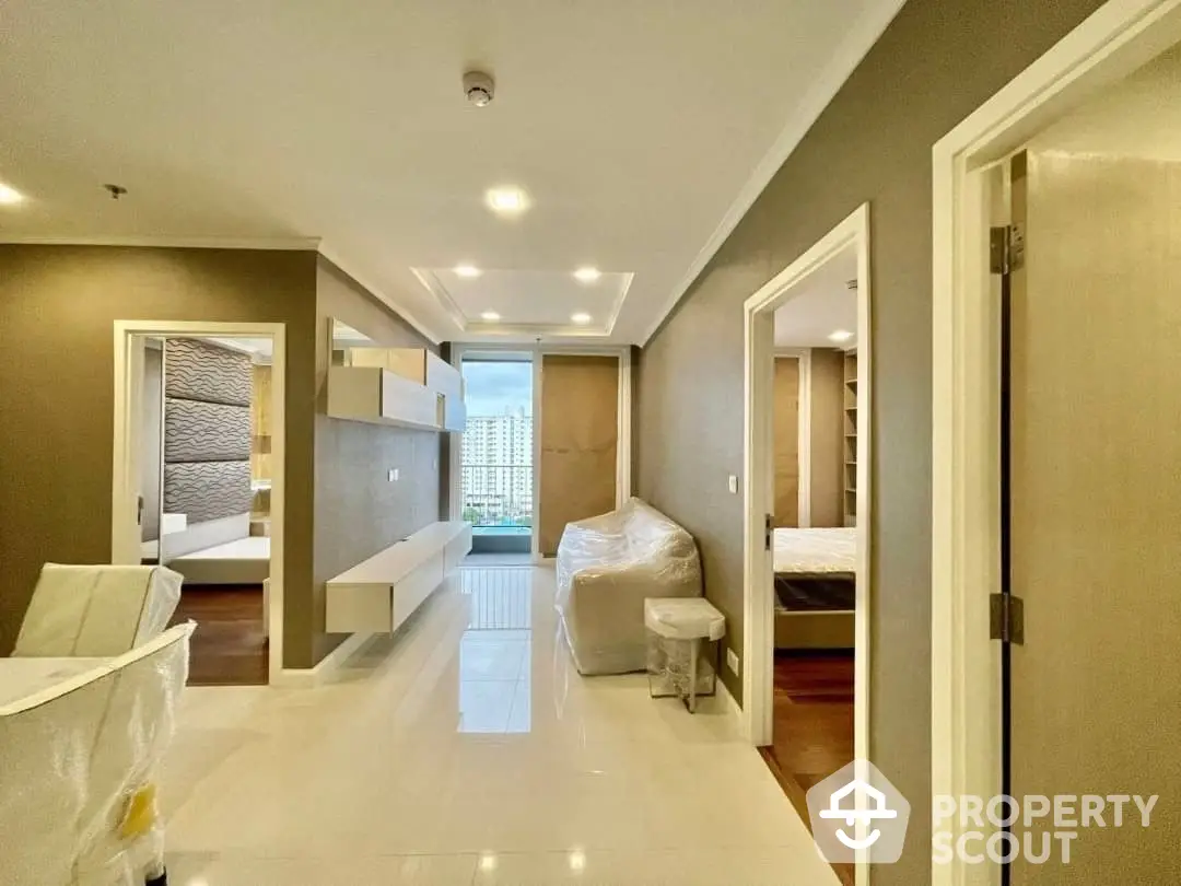 Spacious modern apartment interior with sleek finishes, featuring an open layout connecting living area to bedrooms, ample natural light, and contemporary design.