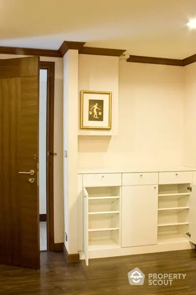 Elegant entryway with sleek white shoe cabinet and warm wooden flooring, highlighted by modern lighting and tasteful artwork.