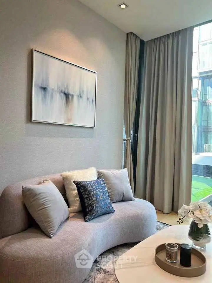 Elegant living room with modern sofa and abstract art, featuring floor-to-ceiling windows and stylish decor.