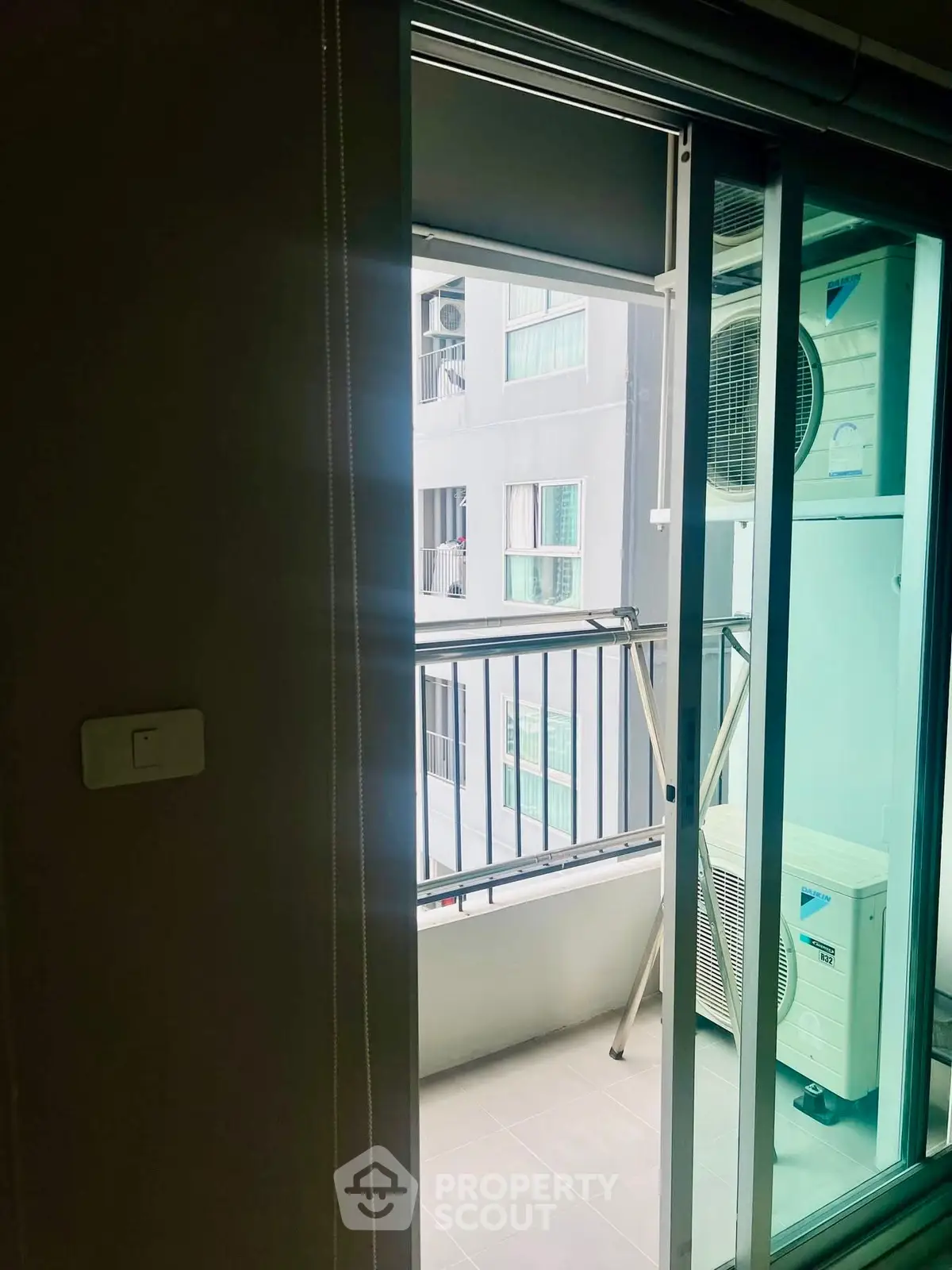 Modern apartment balcony with sliding glass doors and air conditioning unit.