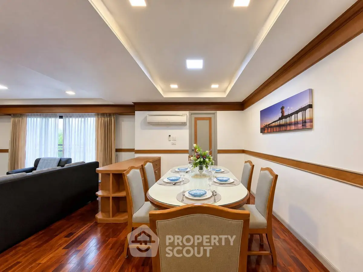 Spacious living and dining area with elegant wooden flooring and modern lighting.