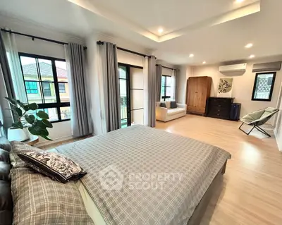 Spacious bedroom with modern decor and large windows offering natural light.