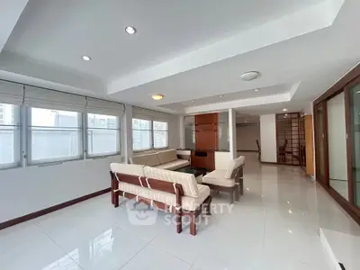 Spacious living room with modern furniture and large windows in a bright apartment.