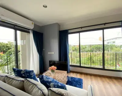 Bright living room with large windows and garden view, featuring cozy sofa and modern decor.