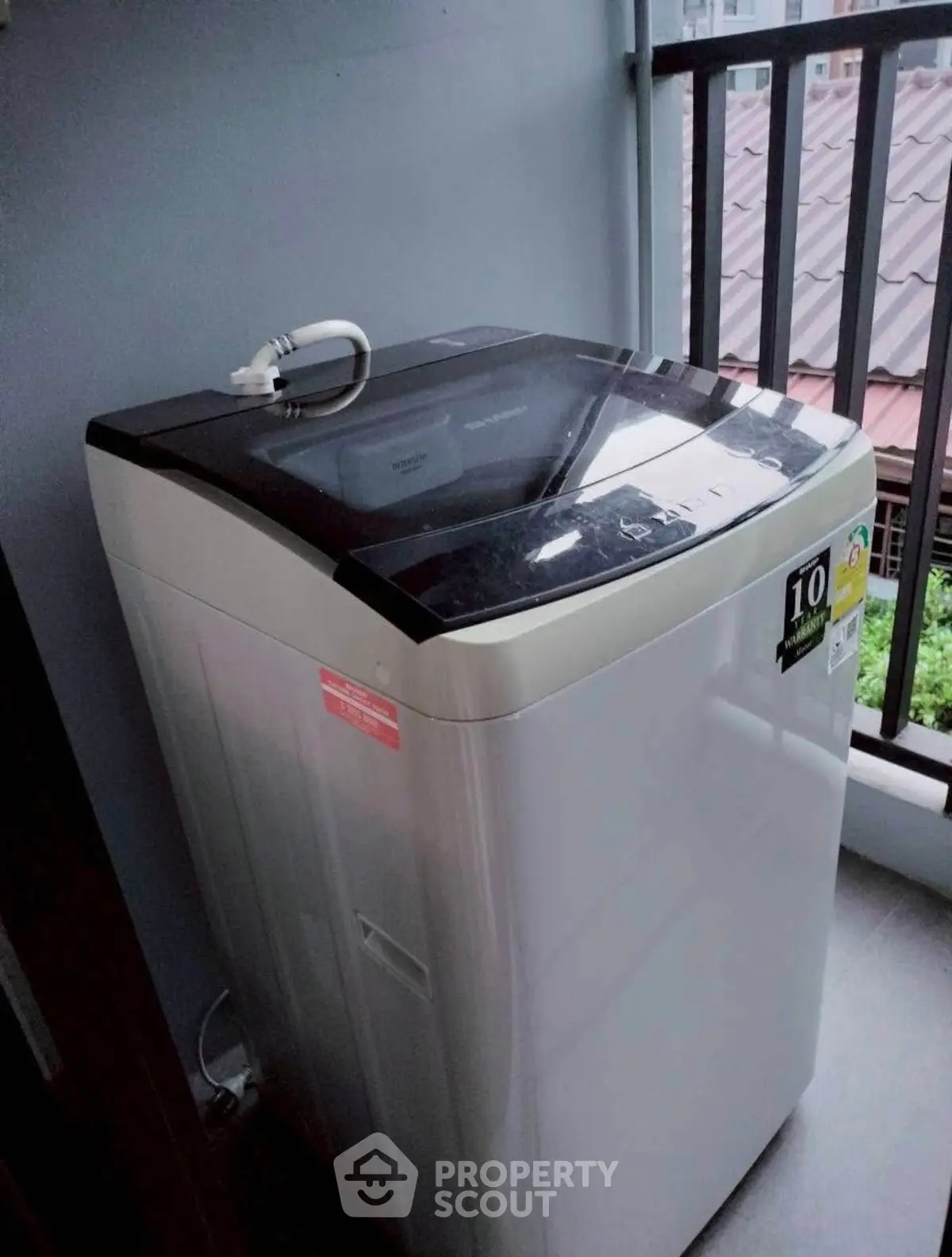 Modern washing machine on a balcony with a view of rooftops, ideal for urban living.