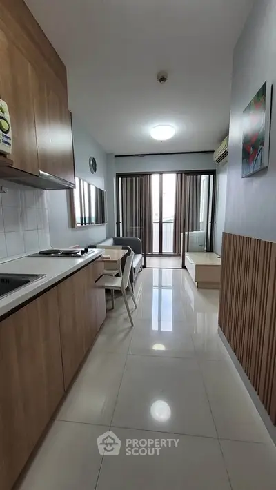 Modern studio apartment with sleek kitchen and cozy living area, featuring large windows for natural light.