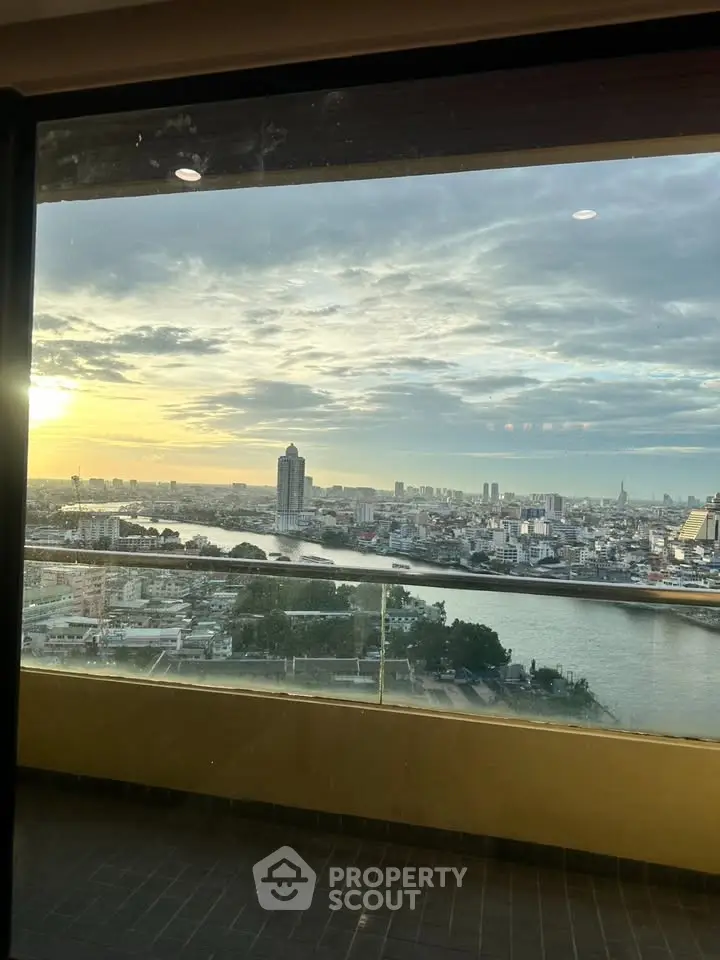 Stunning high-rise view of city skyline and river at sunset from a spacious balcony.