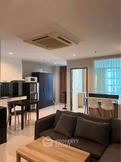 Modern open-plan living room with stylish kitchen and dining area, featuring sleek furniture and contemporary design.