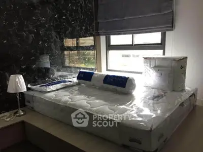 Modern bedroom with new mattress and stylish decor, featuring a sleek lamp and large window for natural light.