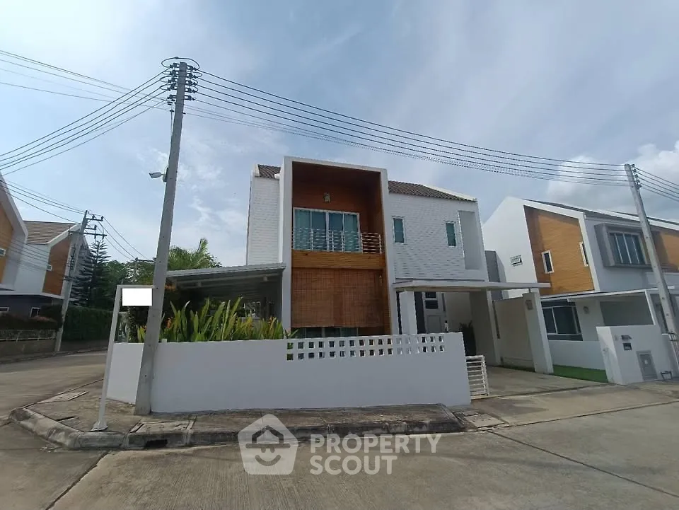 Modern two-story house with unique facade and spacious driveway on a sunny day.