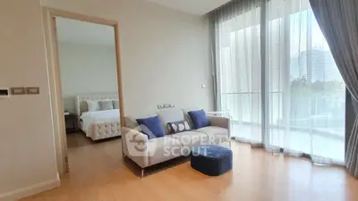 Modern living room with large windows and adjacent bedroom, featuring stylish decor.