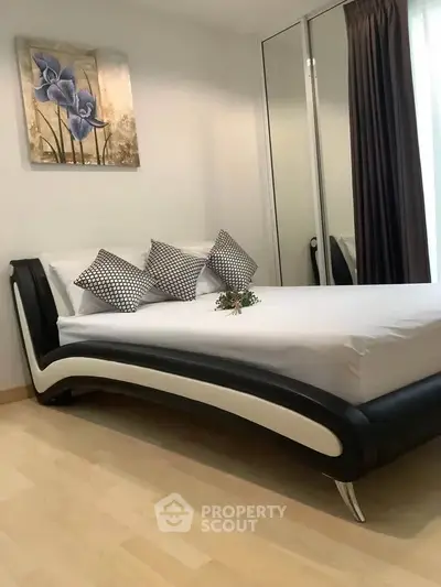 Modern bedroom with stylish bed and mirrored wardrobe in a cozy apartment.
