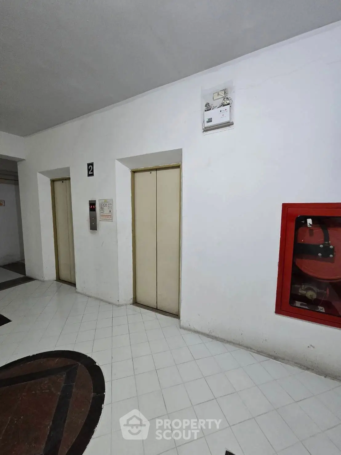 Modern building elevator area with clean white tiles and safety equipment.