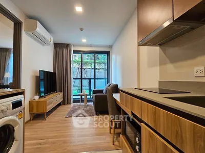 Modern open-layout living room with kitchen, featuring sleek furniture and natural light.