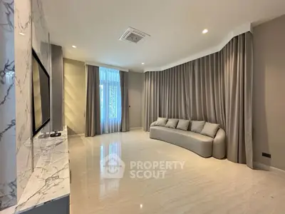 Spacious modern living room with marble accents and elegant curtains.