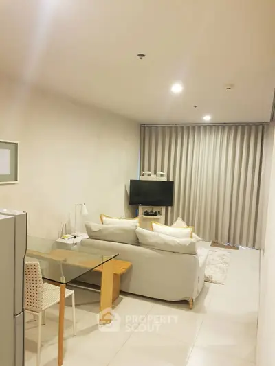 Modern living room with cozy sofa, TV, and dining area in open layout apartment.