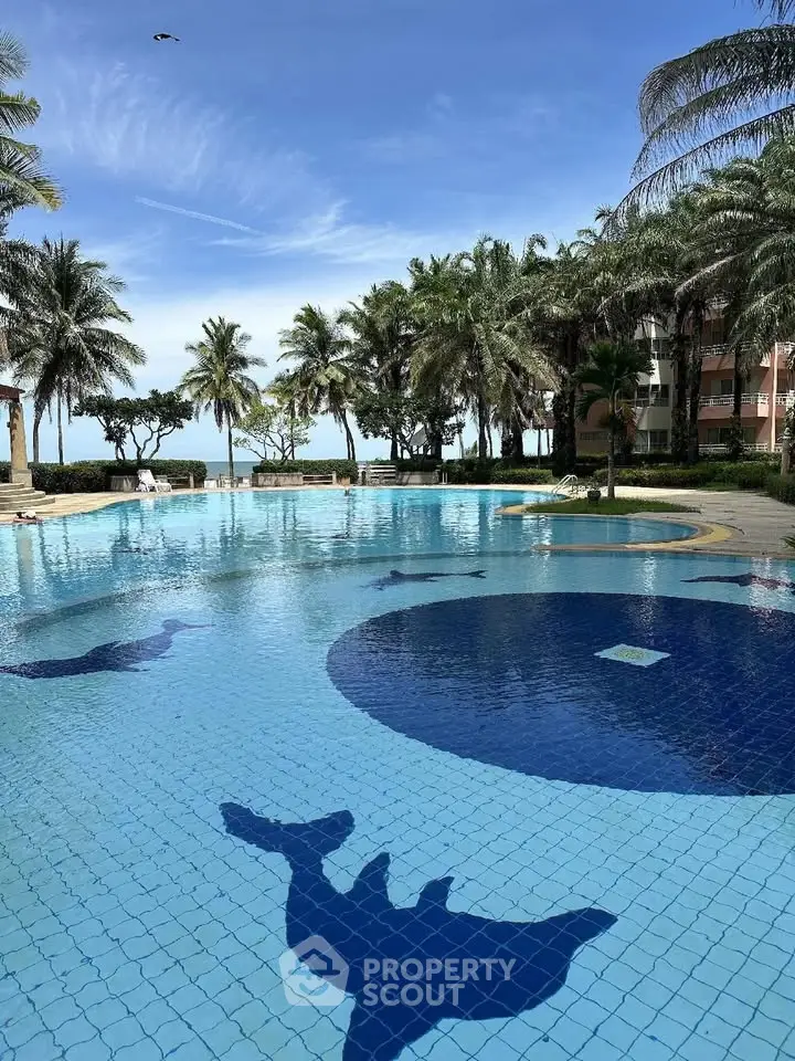 Luxurious beachfront pool with dolphin mosaic and palm trees, perfect for tropical living.