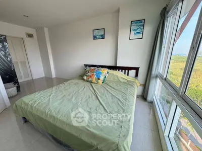 Bright bedroom with large windows and scenic view, featuring a cozy bed and minimalist decor.