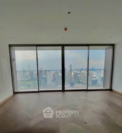 Spacious high-rise apartment with stunning city skyline view through large windows.