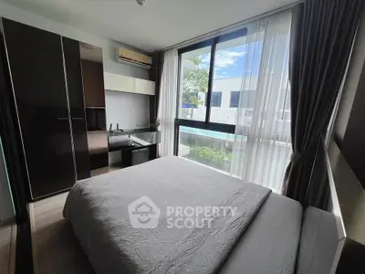 Modern bedroom with large window offering pool view, featuring sleek furniture and ample natural light.