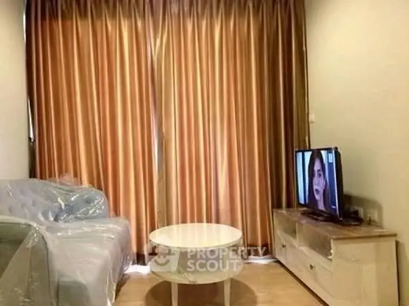 Cozy living room with sofa, TV, and elegant curtains in modern apartment.