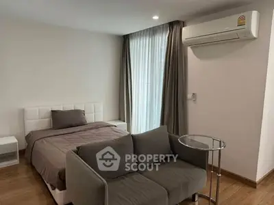 Modern bedroom with cozy sofa and air conditioning in stylish apartment.