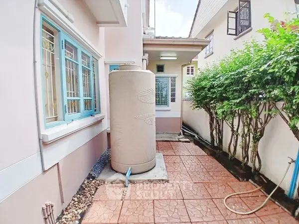 Charming exterior view of a house with a water tank and lush greenery.