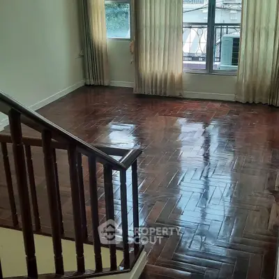 Spacious living room with polished wooden floors and large windows for natural light.