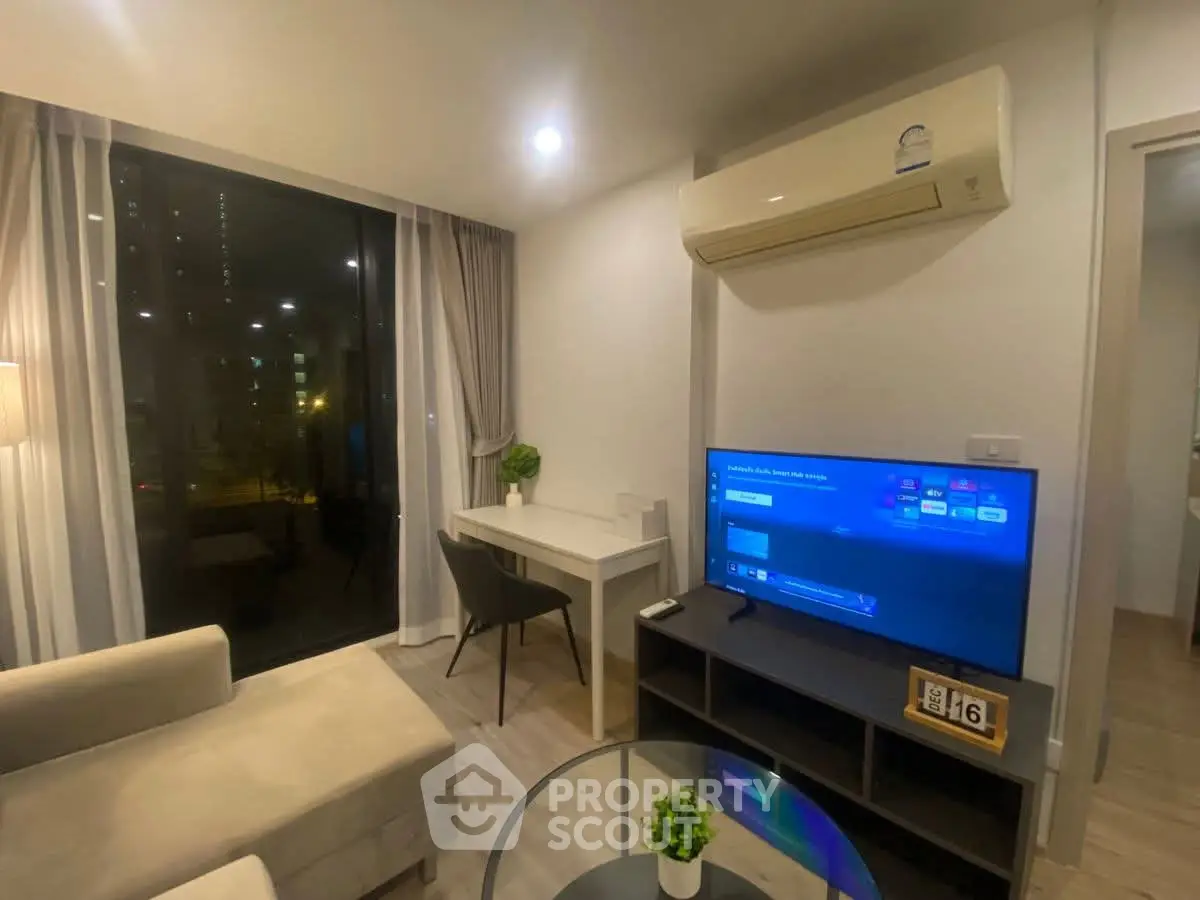 Modern living room with cozy seating, large TV, and stylish decor in a high-rise apartment.