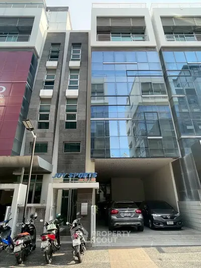 Modern commercial building with parking and glass facade in urban setting.