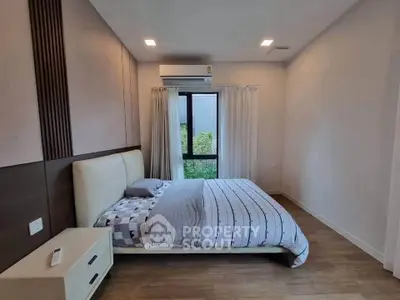Modern bedroom with stylish decor and large window offering natural light.