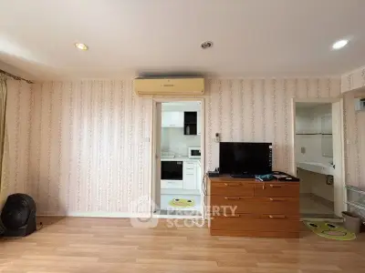 Spacious living room with modern decor and wooden flooring, featuring a TV and air conditioning.