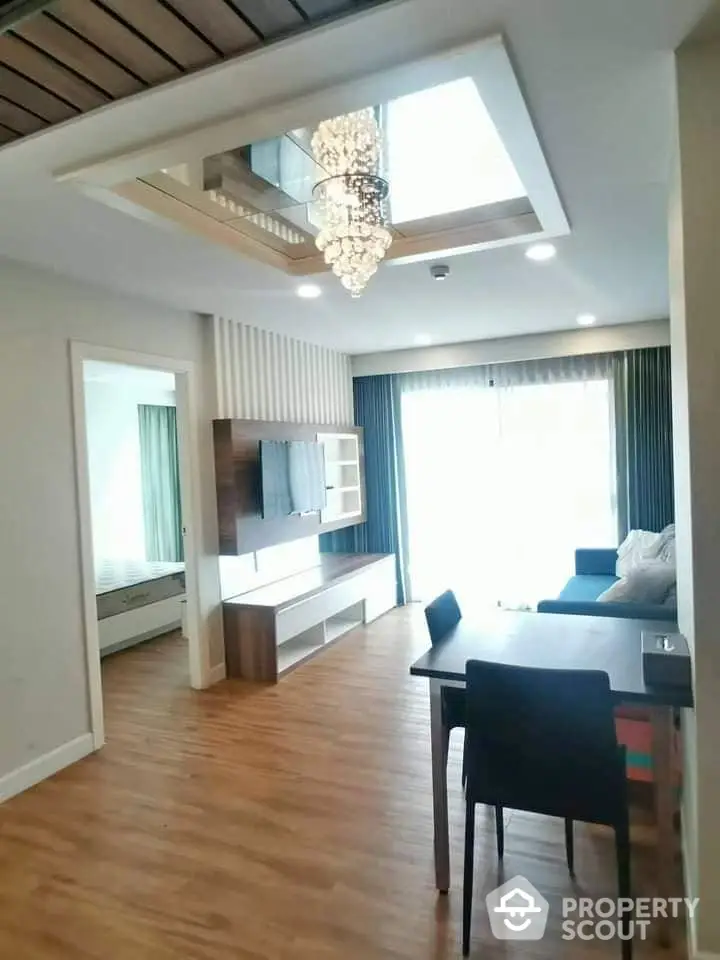 Modern living room with elegant chandelier and wooden flooring in a stylish apartment.