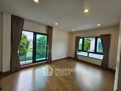 Spacious room with large windows and balcony overlooking lush greenery.