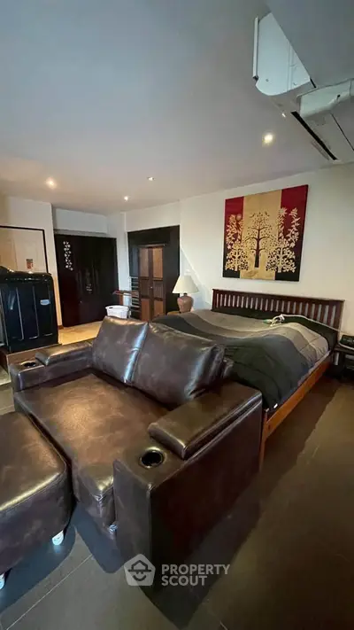 Spacious bedroom with stylish leather sofa and modern decor