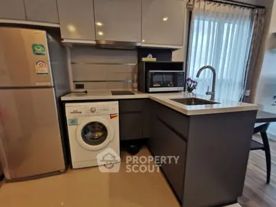 Modern kitchen with washing machine and sleek appliances in a cozy apartment setting.