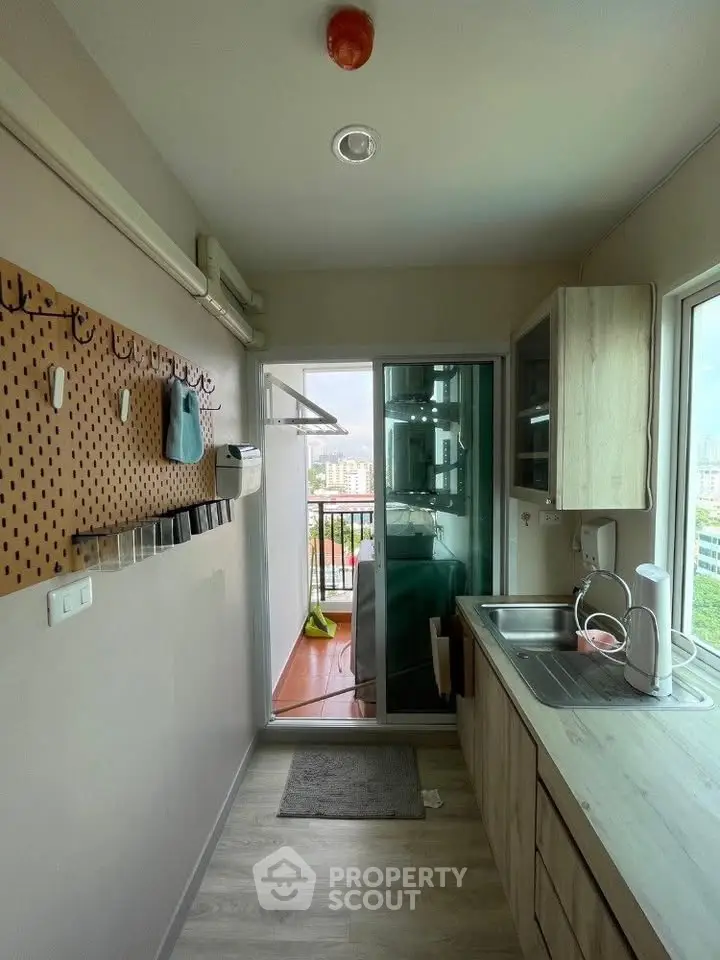 Modern kitchen with balcony view, featuring sleek cabinetry and ample natural light.