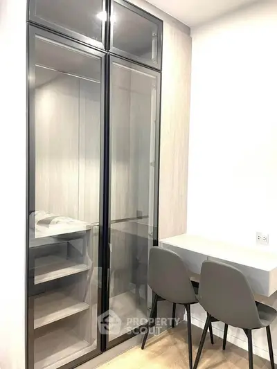 Modern study area with sleek glass cabinet and minimalist desk in a stylish apartment.