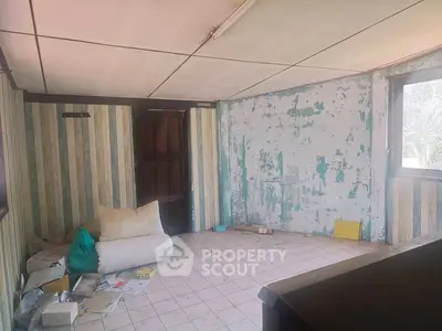 Spacious room with potential for renovation, featuring large window and tiled floor.