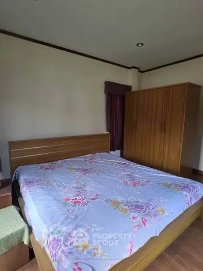 Cozy bedroom with wooden furniture and floral bedding in a serene setting.