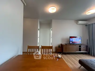 Modern living room with wooden dining table and TV unit, featuring sleek design and cozy ambiance.