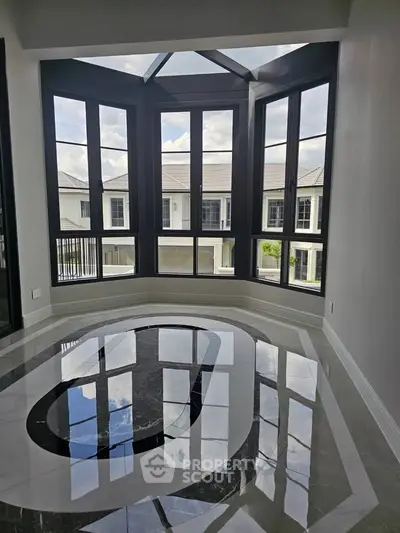 Luxurious modern living room with large bay windows and glossy marble flooring, offering a stunning view of the neighborhood.