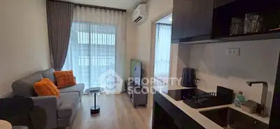 Modern open-layout living room with cozy sofa, TV, and kitchen area in stylish apartment.
