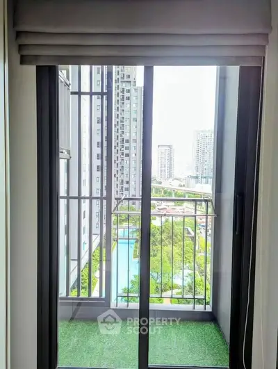 Modern apartment balcony with stunning cityscape and pool view, featuring sleek glass doors and lush greenery.