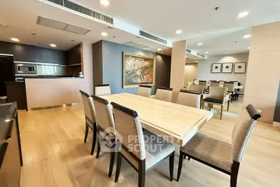 Spacious modern dining area with elegant wooden table and chairs, open kitchen layout, and stylish decor.