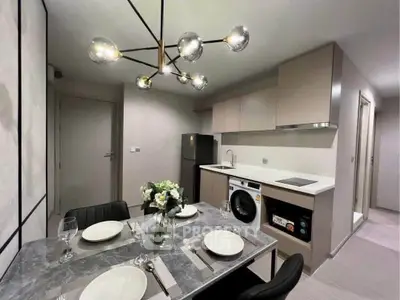 Modern kitchen with dining area, featuring sleek cabinetry, washing machine, and elegant lighting.
